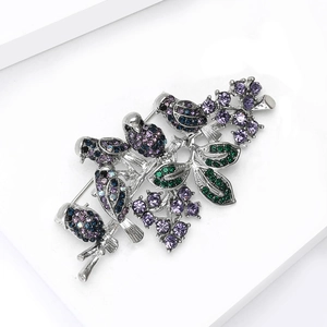 Detailed macro view of colorful crystal bird brooch with silver metal base and pin closure