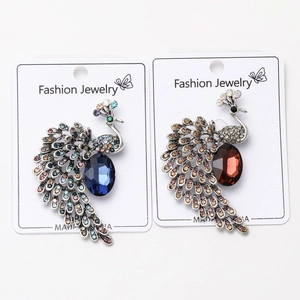 Détail de broches en forme de paon ornées de strass bleus et ambrés sur support métallique