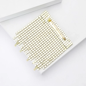Detail view of the golden mesh tassel brooch with flexible metal square grain texture