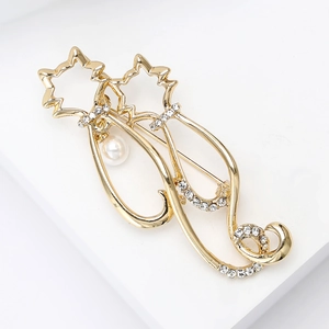Détail de broche chat dorée avec strass scintillants et perle blanche élégante