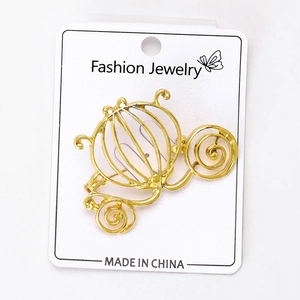 Detailed macro of golden hollow pumpkin carriage brooch on a white jewelry card display