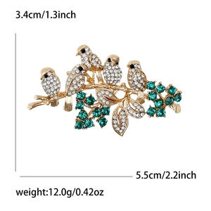 Elegant gold bird brooch on tree branch with sparkling crystals and green gemstones