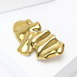 Macro detail of gold wave brooch with liquid metal texture on white platform
