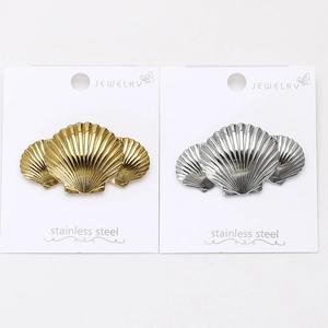 Detail of shell-shaped stainless steel brooches in polished gold and silver finishes