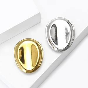 Detailed view of polished oval geometric metal brooches in gold and silver finishes