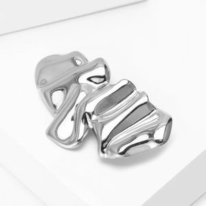 Macro shot of polished silver wavy textured brooch with liquid metal design and glossy finish