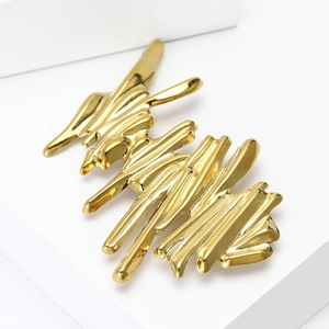 Macro view of abstract gold wave brooch with fluid texture and high-gloss mirror finish