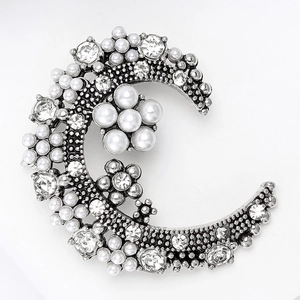 Détail de la broche lune argentée vintage avec fleurs en perles et strass brillants