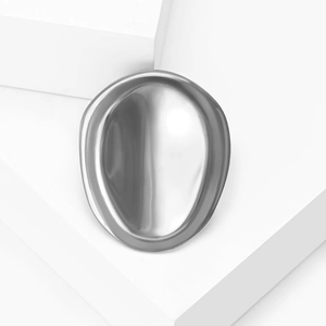 Polished stainless steel geometric oval brooch on a minimalist white platform stand