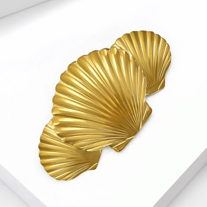Detailed macro view of three golden geometric shell brooches with sunburst metal texture