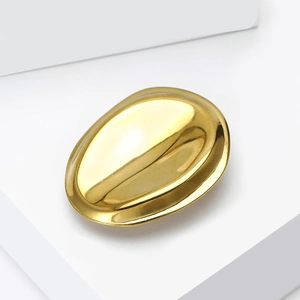 Polished gold geometric brooch with minimalist oval design on white architectural stand