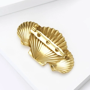 Elegant gold-tone triple shell brooch with geometric radiating textures on white background