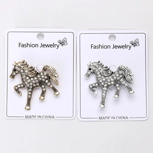 Detailed macro view of vintage gold and silver horse brooches with micro rhinestones