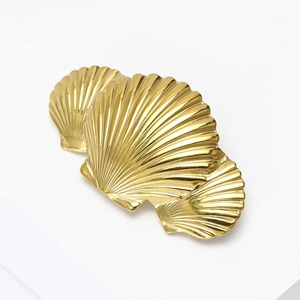 Macro view of three gold scallop shell brooches with detailed radial texture and metallic finish