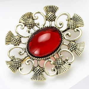Détail macro de broche chardon rétro avec pierre rouge ovale et métal doré évidé vintage