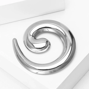 Macro view of snail-shaped silver spiral ear weights with polished mirror finish