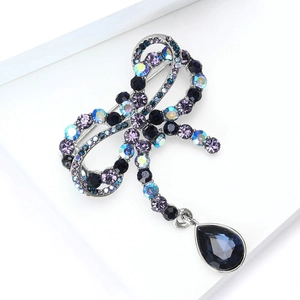 Macro detail of French vintage bow brooch with purple rhinestones and blue crystal drop