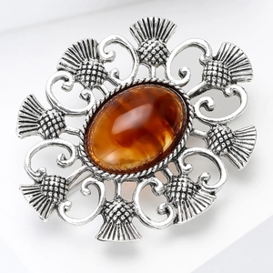 Vue rapprochée d'une broche chardon vintage avec pierre ambre et métal ciselé