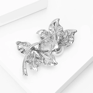 Vue détaillée d'une broche feuille en argent avec une perle blanche élégante et son épingle