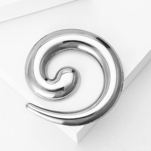 Polished stainless steel spiral ear taper placed on a white geometric display stand