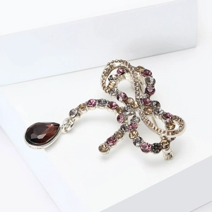 Macro detail of retro bow brooch featuring multicolor rhinestones and a brown teardrop gem