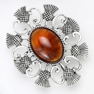 Détail macro d'une broche chardon vintage en argent avec incrustation d'ambre et ajourage