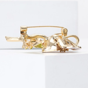 Detailed back view of golden flower brooch featuring classic safety pin clasp and metal texture