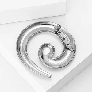 Macro shot of silver spiral brooch showing polished metal finish and sturdy pin clasp