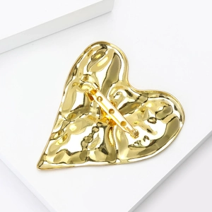 Luxe gold heart brooch with hammered texture and secure pin clasp on a white base