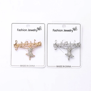 Detail of cat and musical note brooches with sparkling rhinestones in gold and silver
