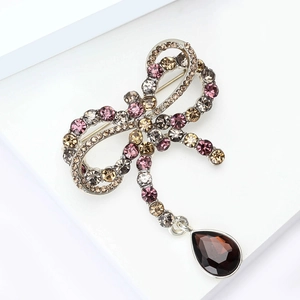 Macro detail of French bow brooch with pink rhinestones and a brown water drop pendant