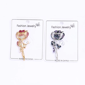 Détail de broches en forme de rose serties de strass en cristal et d'une perle blanche