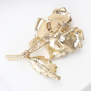 Close-up of the golden flower brooch back showing safety pin clasp and metal texture