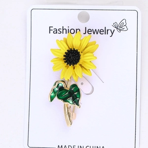 Vue détaillée de la broche tournesol en émail jaune avec feuilles vertes sur carte bijoux