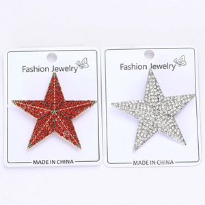 Detailed close-up of red and silver star brooches with rhinestones on white display cards