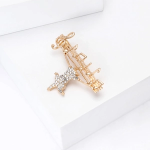 Detail of music note brooch with crystal dog on white geometric podium display