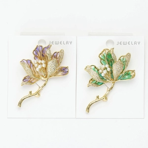 Detailed macro view of purple and green enamel lotus brooches with pearls and crystals