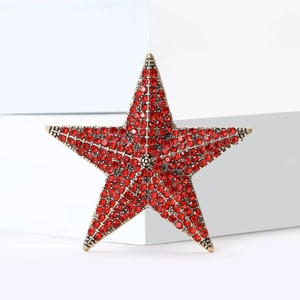 Macro shot of gold star brooch with red rhinestones on a minimalist white background