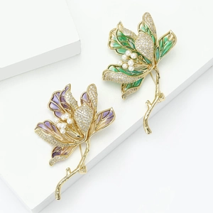 Elegant lotus flower brooches with rhinestones and pearls on a white geometric stand