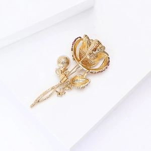 Détail d'une broche fleur dorée élégante ornée de strass roses et d'une perle