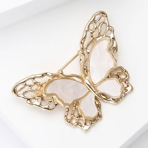 Detailed macro view of golden double-layer butterfly brooch with white shell inlay textures