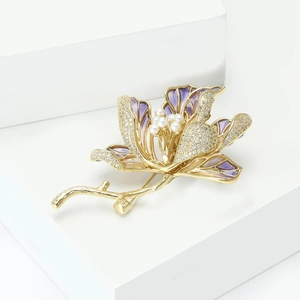 Detail of luxury magnolia brooch with purple enamel petals, pearls, and gold plating