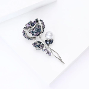 Détail de la broche rose avec des strass bleu-violet et une perle blanche élégante