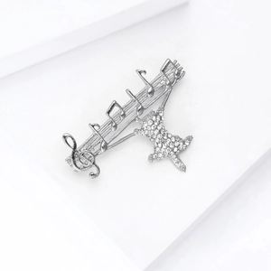 Close-up of music themed cat brooch with crystal notes on white geometric stairs
