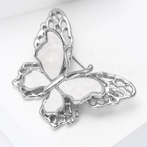 Detailed view of silver butterfly brooch with shell inlay and hollow filigree design