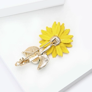 Vue arrière détaillée d'une broche tournesol en émail jaune avec épingle de sûreté dorée
