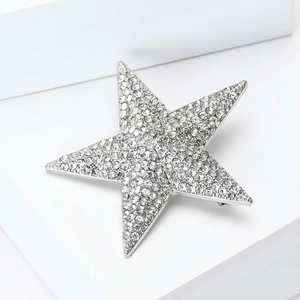 Macro shot of silver star brooch with pavé rhinestones on minimalist white block