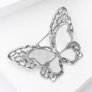 Detail of the butterfly brooch featuring intricate hollow metalwork and shell inlay