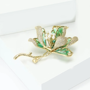 Detail of luxury lotus brooch with green enamel, crystals, and pearls on gold base