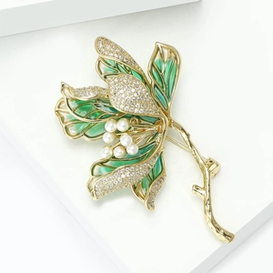 Detailed macro view of gold lotus brooch with green enamel petals and white pearls